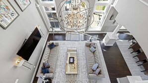 A spacious living area with a large chandelier, a sofa set, and a coffee table. - Pool + Cabana + Amazing Views - Picturesque Point (Austin)