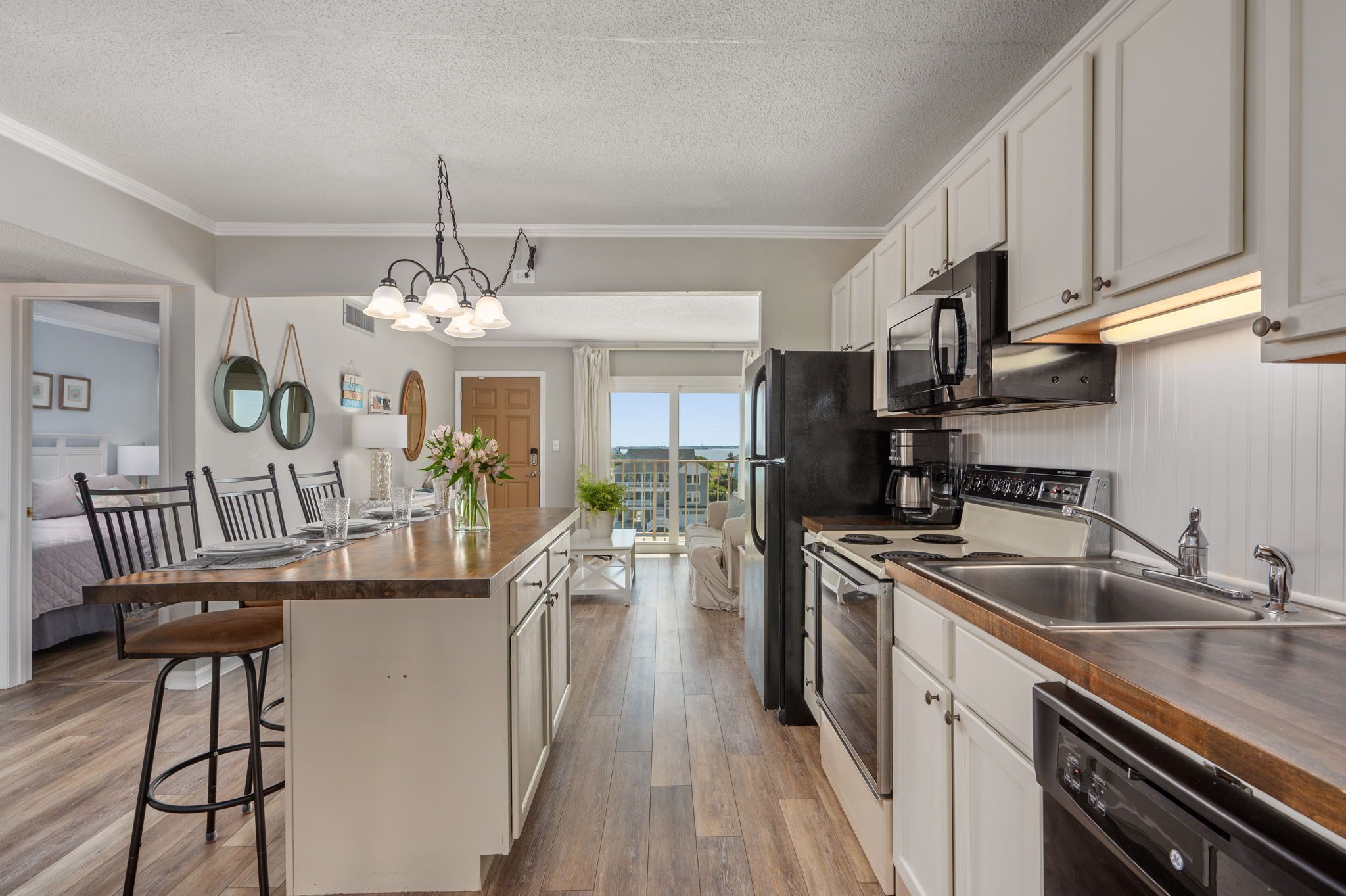 A modern kitchen with a central island, stainless steel appliances, and a view to the outside.