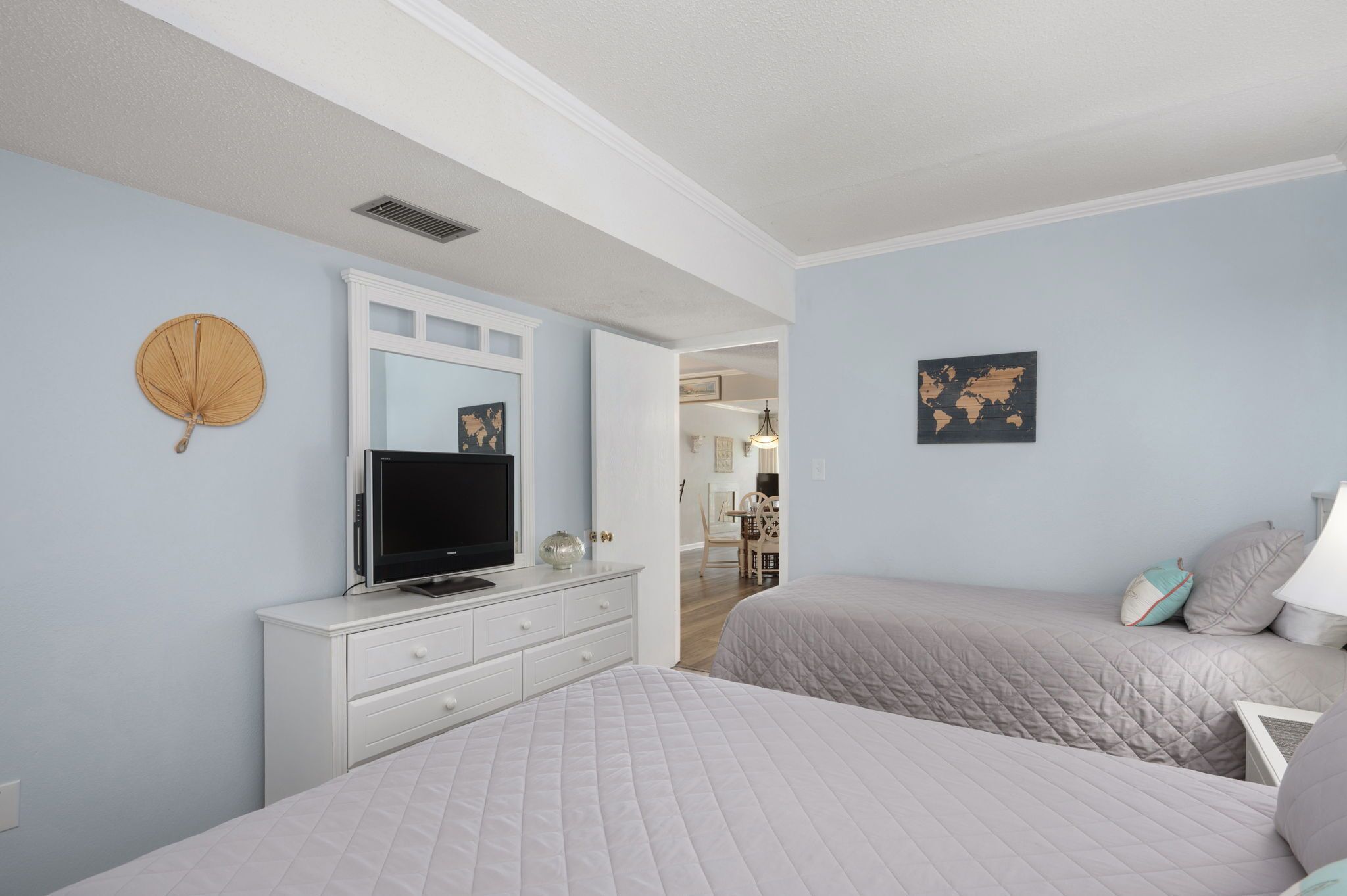 A bedroom with two beds, a TV on a dresser, and a world map on the wall.