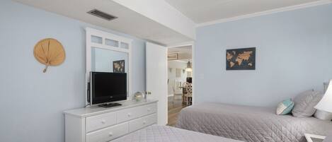 A bedroom with two beds, a TV on a dresser, and a world map on the wall.