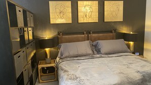 Una camera da letto con un letto, due lampade da comodino, un tavolino e tre opere d'arte appese al muro.