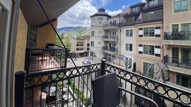 Un balcone con vista su un edificio a più piani con balconi, una scala in pietra e una montagna sullo sfondo.