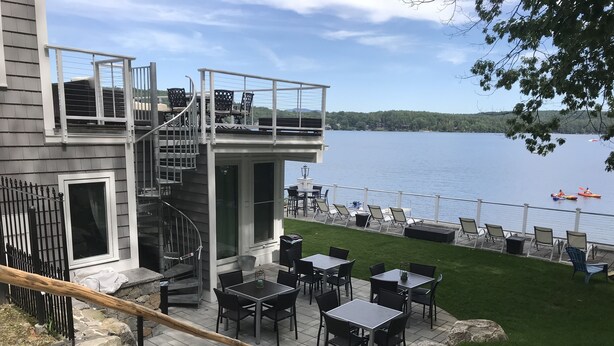 Une terrasse avec des sièges extérieurs et une vue sur le lac.