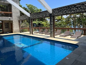A swimming pool with lounge chairs and a stone wall. - Excellent house in Angra with private beach - 10 bedrooms, 8 of which are suites. (Angra dos Reis)
