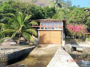 A house with a garage, surrounded by palm trees and a small garden. - Excellent house in Angra with private beach - 10 bedrooms, 8 of which are suites. (Angra dos Reis)