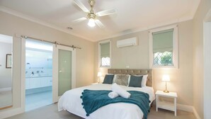 A bedroom with a bed, a ceiling fan, a nightstand, and a window. - Wandew - Echuca Holiday Homes (Echuca)