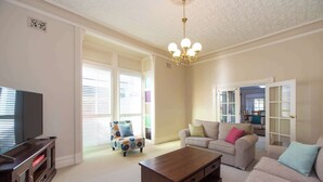 A living room with a TV, a coffee table, two sofas, and a patterned armchair. - Wandew - Echuca Holiday Homes (Echuca)