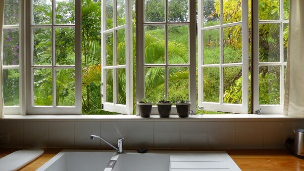 Eine Küche mit einem großen Fenster, einem Spülbecken und Blumentöpfen an der Fensterbank.