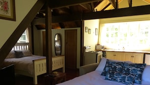 Ein Schlafzimmer mit einem großen Bett, einem kleineren Bett, einem Spiegel, einer Kommode und einer Küchenzeile.