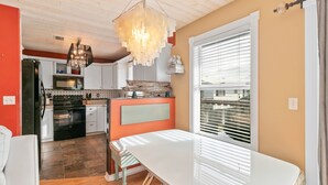 Una cocina con techo de madera, una mesa de comedor y vistas a través de una ventana con persianas.