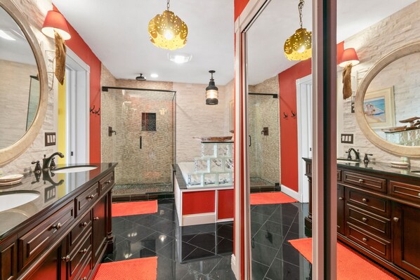 Un baño moderno con un espejo grande, lavamanos dobles y un tocador con cubierta de vidrio.