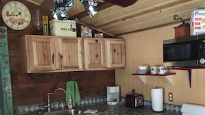 Una cocina compacta con armarios de madera, un microondas, un tostador y una estufa.