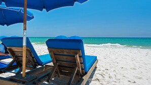 A beach with wooden lounge chairs and blue umbrellas. - Calypso 6th floor with Gulf Master - Beach Chairs & FREE Activities each day! (Panama City Beach)