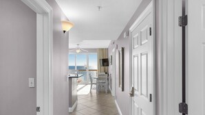 A hallway leading to a balcony with a view of the sea, white doors, and a ceiling fan. - Calypso 6th floor with Gulf Master - Beach Chairs & FREE Activities each day! (Panama City Beach)