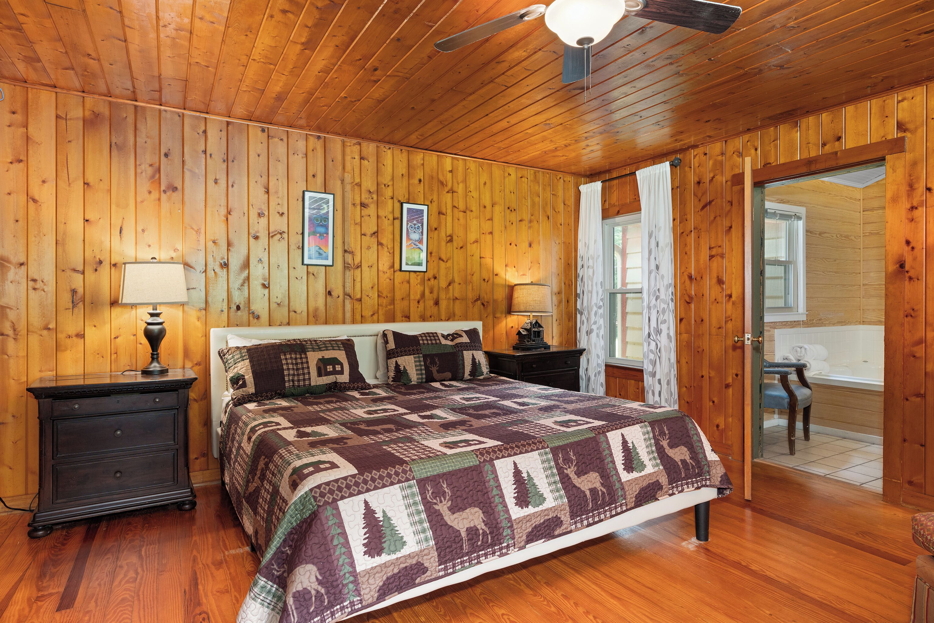 Un dormitorio con paneles de madera, una cama, mesitas de noche y una puerta que da a un baño.