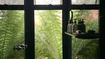 A bathroom with a large window, a mirror, and a shelf with toiletries.