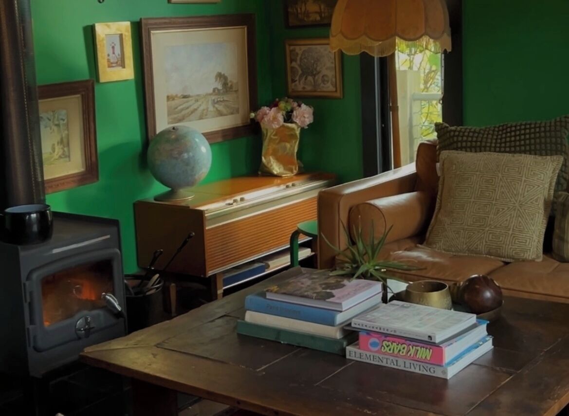 A cozy room with a wooden table, books, a globe, framed pictures, and a green wall.