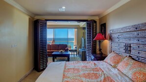 Une chambre d’hôtel avec un grand lit, un bureau, une chaise et une vue sur l’océan.