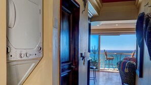 Une buanderie équipée de machines à laver et de sèche-linge superposés, une porte en bois et un balcon avec vue.