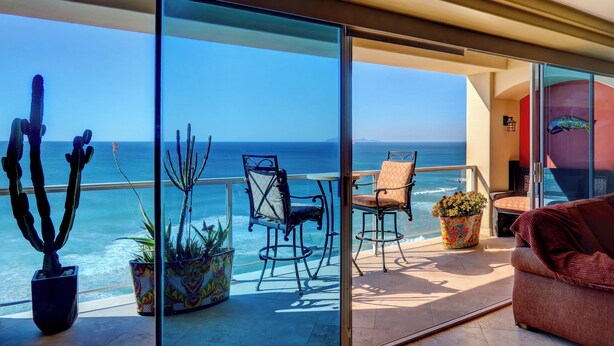 Un balcon avec vue sur l’océan, agrémenté de plantes en pot, de chaises et d’un canapé.