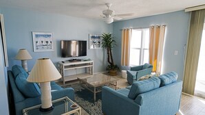 Ein Wohnzimmer mit Sofa, Couchtisch, Fernseher und Deckenventilator.