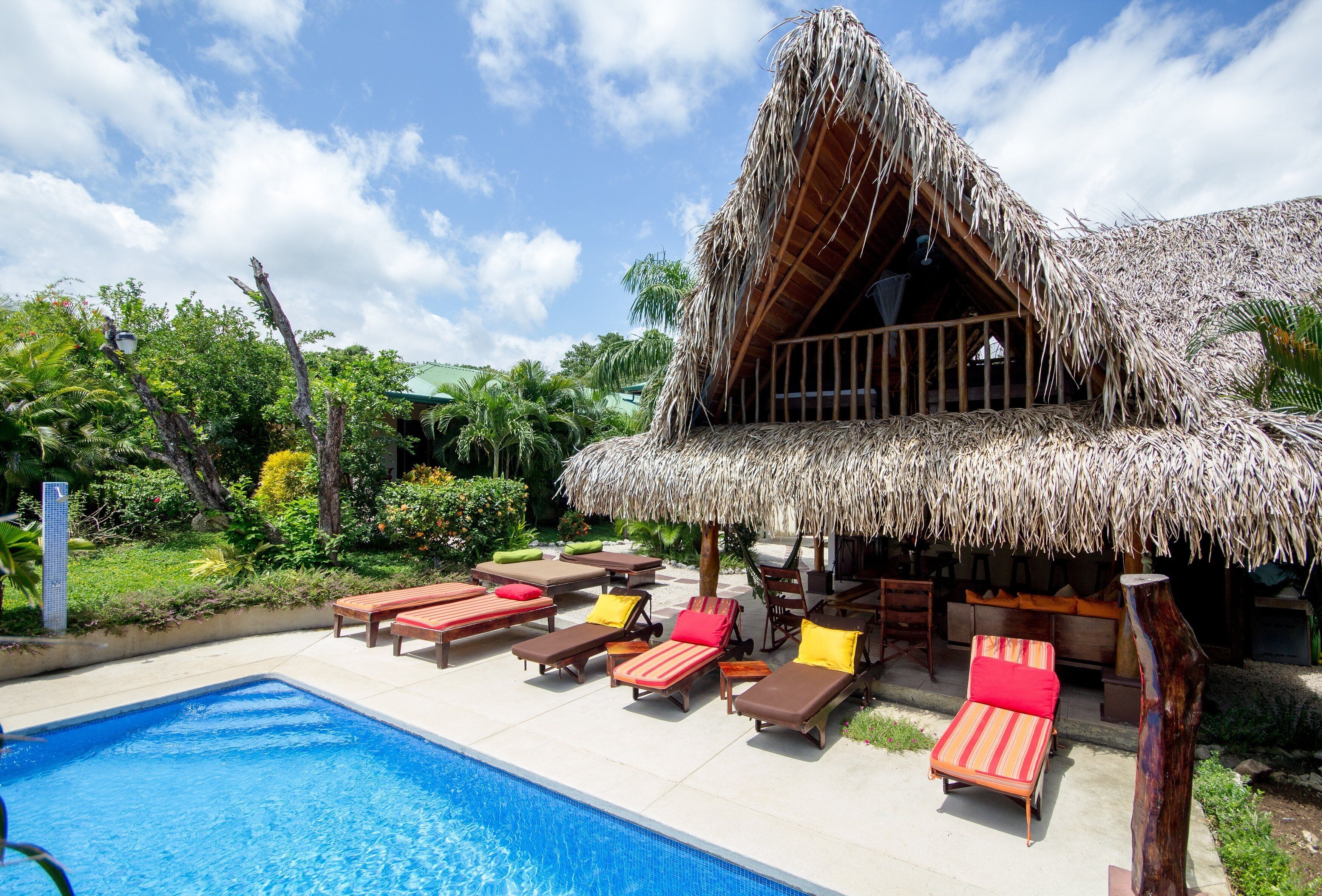 A pool area with lounge chairs and a thatched-roof structure.