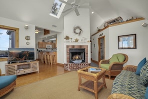 A spacious living room with a fireplace, wicker furniture, and a television.