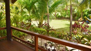 Une terrasse en bois offrant une vue sur un jardin luxuriant et une piscine.