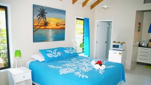 Une chambre avec un lit, une table de chevet, un tableau, une salle de bain et un coin cuisine.
