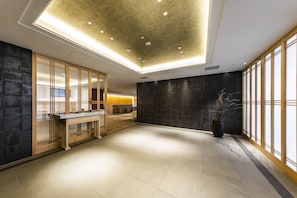 A spacious lobby with a modern design, featuring a reception desk, a large dark wall, and a potted plant. - JR WEST GROUP VIA INN Prime SHINSAIBASHI YOTSUBASHI (Osaka)