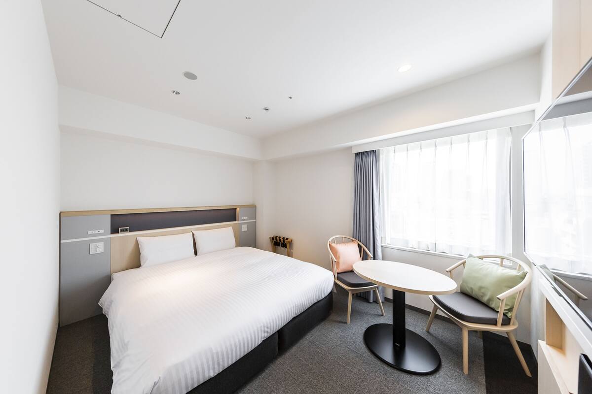 A hotel room with a bed, a round table, and a chair.