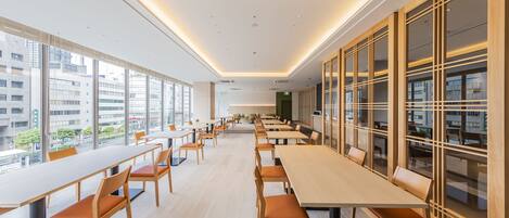 A modern conference room with long tables and chairs, large windows, and a view of the cityscape.