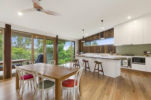 A modern kitchen with a wooden island, bar stools, and a dining table with chairs.