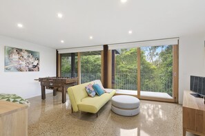 A spacious living area with a sofa, ottoman, and foosball table.