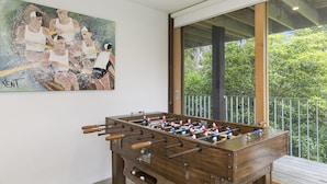 A foosball table in a room with a large window and a painting on the wall.