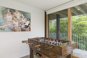 A foosball table in a room with a large window and a painting on the wall.