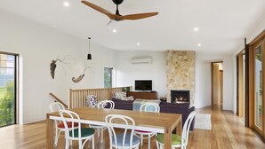 A modern living room with a dining area, a fireplace, and a ceiling fan.