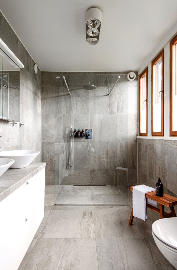 Un baño moderno con un lavabo grande, un inodoro, zona de ducha y tocador con espejo.