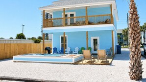 Une propriété de deux étages située en bord de mer, dotée d’une piscine, d’un espace salon extérieur et d’une terrasse en bois.