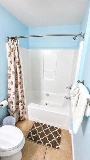 Een bad/douchecombinatie, handdoeken, zeep, toiletpapier