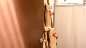 A bathroom with a wooden towel rack holding several towels and a shower curtain. - Las Avellanas Villas Costa Rica - Full equipped house(max 2p) (Santa Cruz)