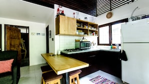 A compact kitchen with a wooden table and stools, a microwave, and a refrigerator. - Las Avellanas Villas Costa Rica - Full equipped house(max 2p) (Santa Cruz)