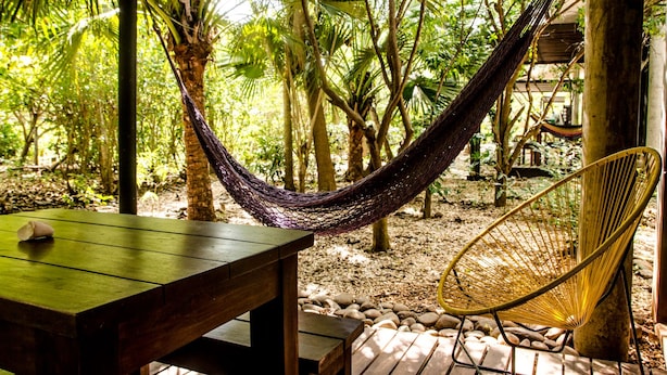 A hammock between trees, a wooden table, and a wicker chair in a forested area. - Las Avellanas Villas Costa Rica - Full equipped house(max 2p) (Santa Cruz)
