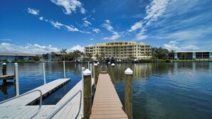 A waterfront hotel with a dock leading to the water, surrounded by palm trees and a clear sky. - Turtle Beach - Gulf-Front Condo - 2BR - Free Boat Docks - Siesta Key (Siesta Key)