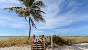 A wooden staircase leading to a beach with a palm tree and a warning sign. - Turtle Beach - Gulf-Front Condo - 2BR - Free Boat Docks - Siesta Key (Siesta Key)