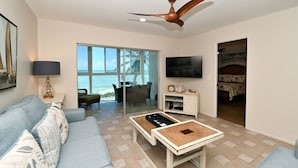 A modern living room with a sofa, coffee table, TV, and a ceiling fan. - Turtle Beach - Gulf-Front Condo - 2BR - Free Boat Docks - Siesta Key (Siesta Key)