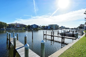 A waterfront dock with a grassy area and buildings in the background.