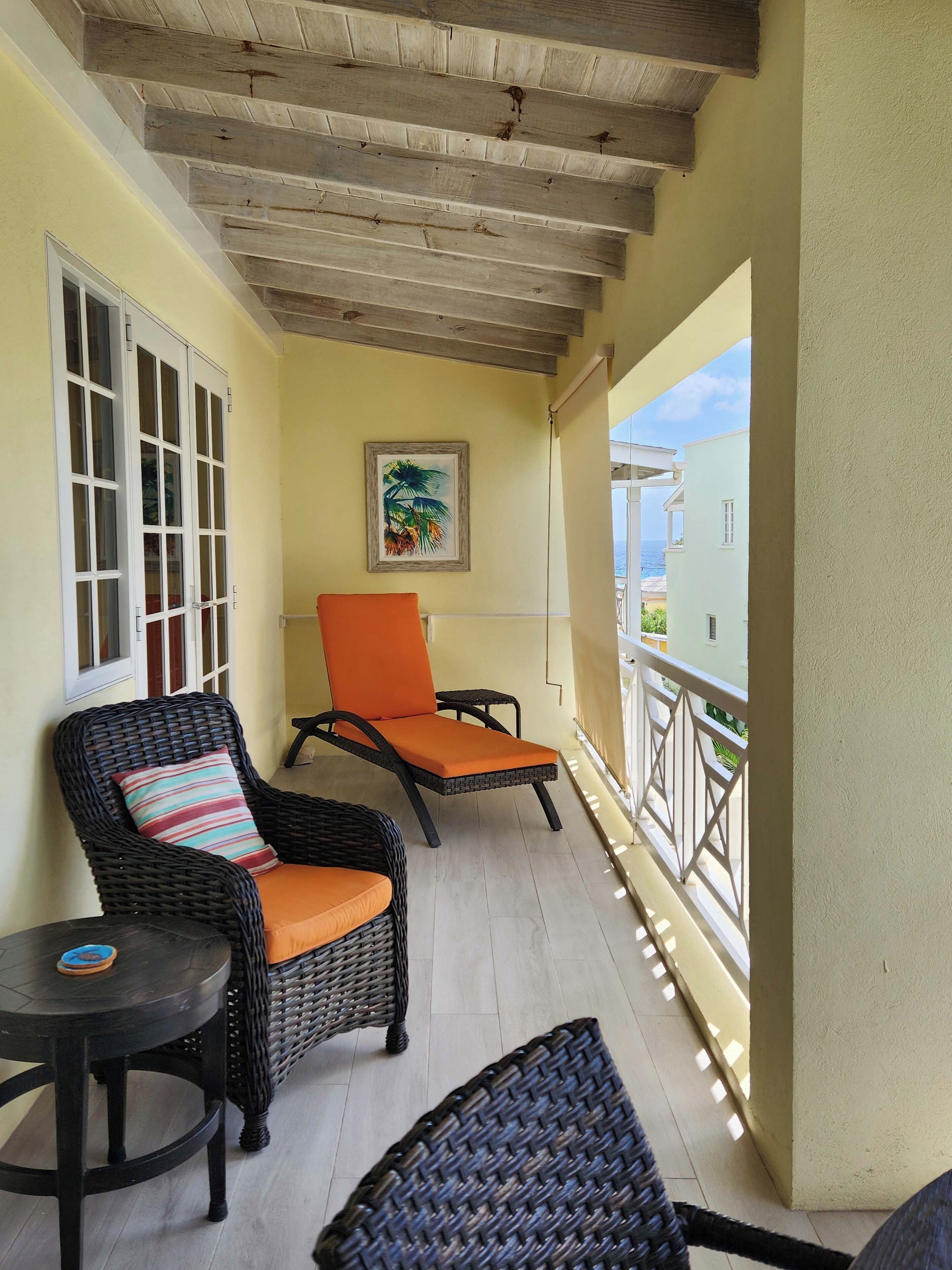 A balcony with wicker furniture, a wooden ceiling, and a view of the sea.