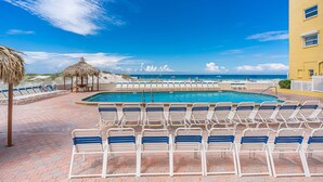 Ett område vid poolen med solstolar, en pool och utsikt över havet.