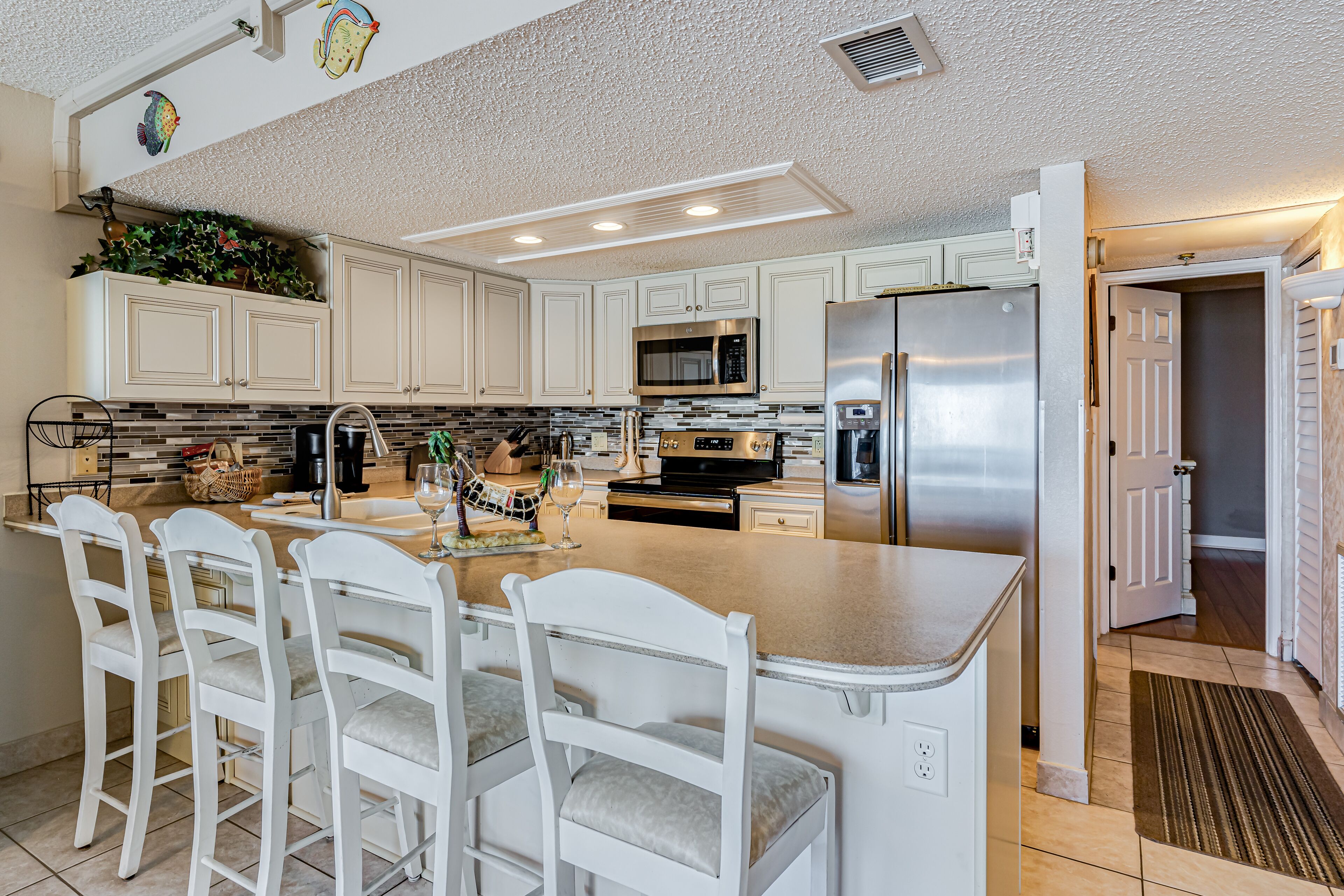 A modern kitchen with white cabinetry, stainless steel appliances, and a central island with bar stools.